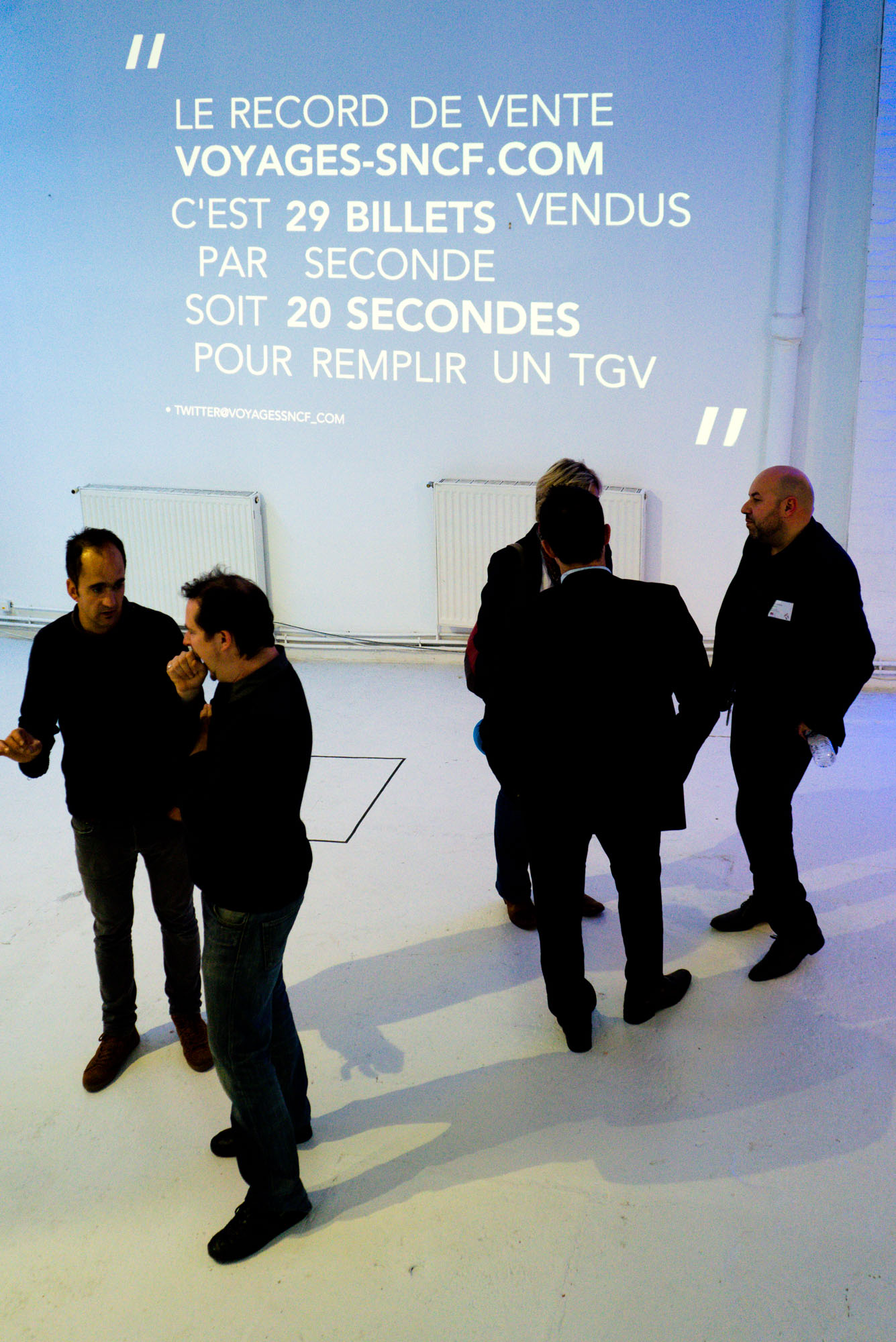 Photographie d'homme habillé en noir devant une projection de statistiques SNCF