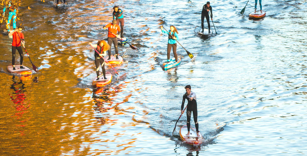 Dizaine de personnes en paddle sur l'eau en train de ramer sur une rivière calme