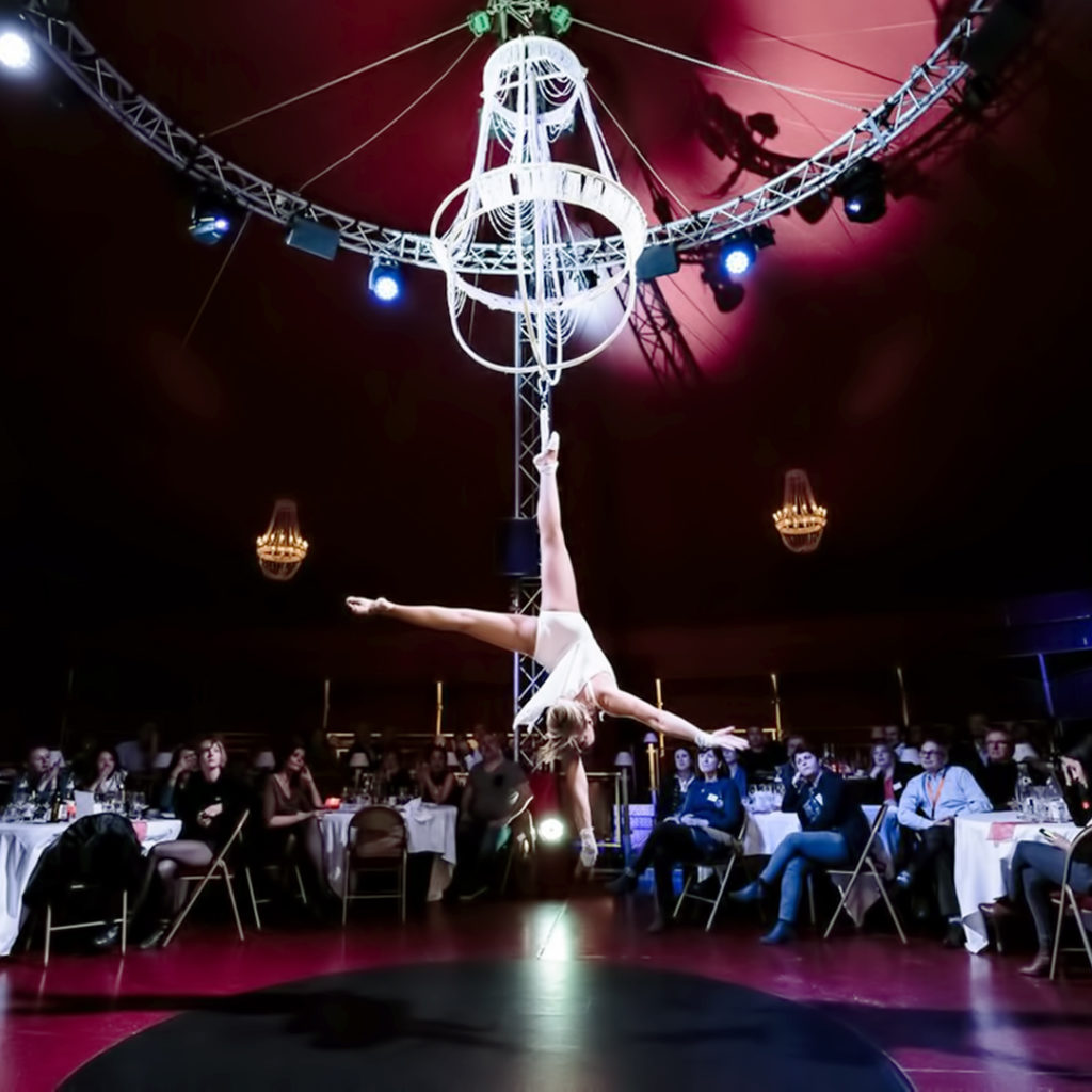 Acrobate en gros plan au milieu d'un cirque et devant des spectateurs