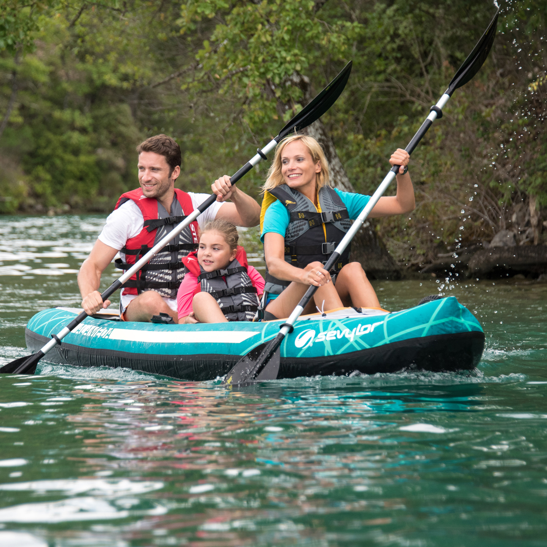 Une famille avec un père, une mère et une fille naviguent sur un kayak gonflable