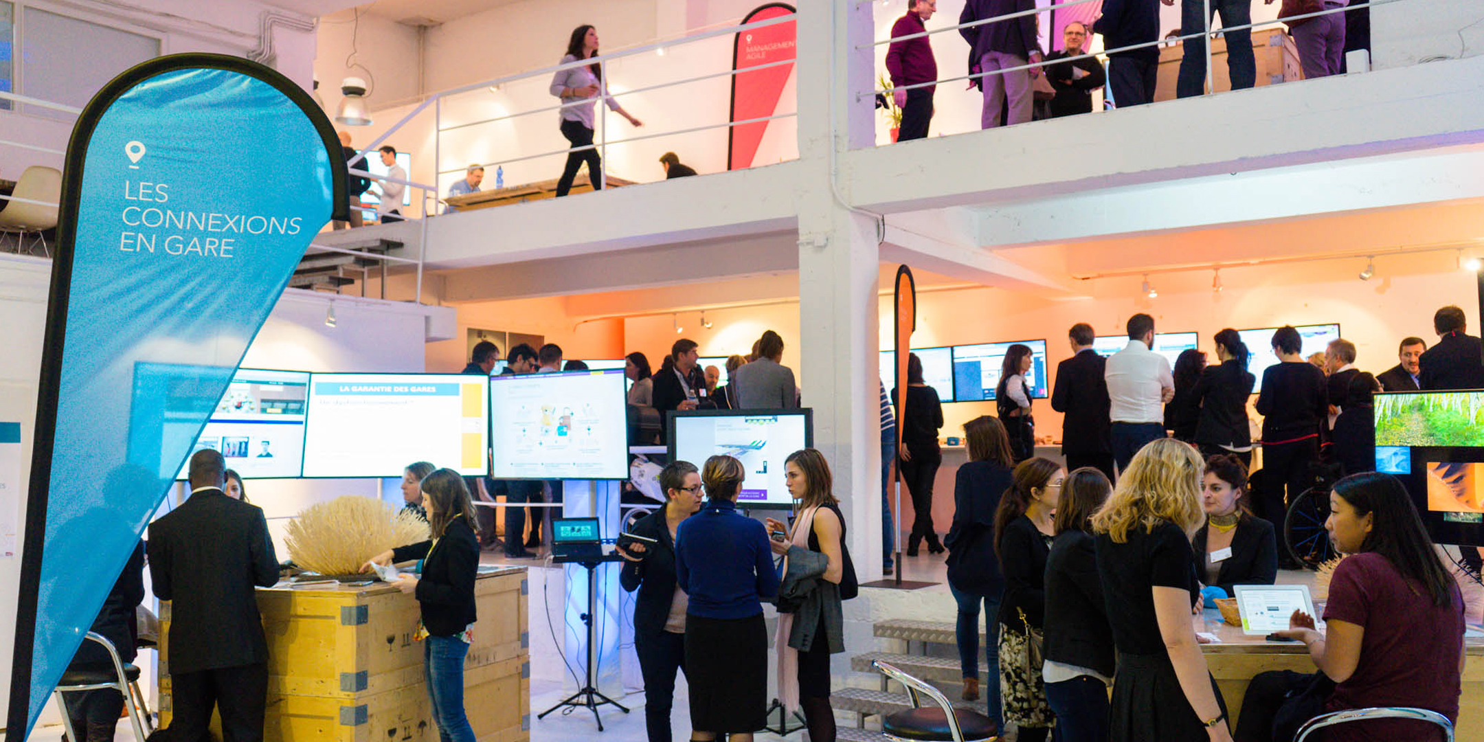 Personnes qui discutent autours d'ateliers évoquant la transformation digitale en gare