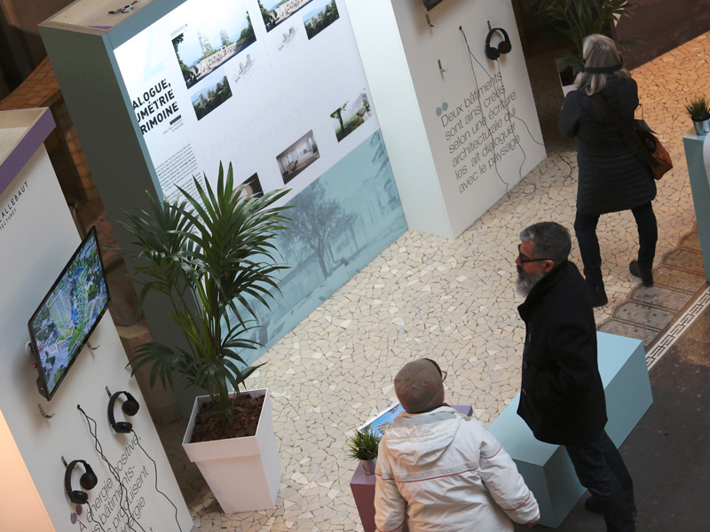 Personnes prenant connaissance des informations sur des corners de présentation de programmes immobiliers pour les thermes de la ville d'Aix-les-Bains