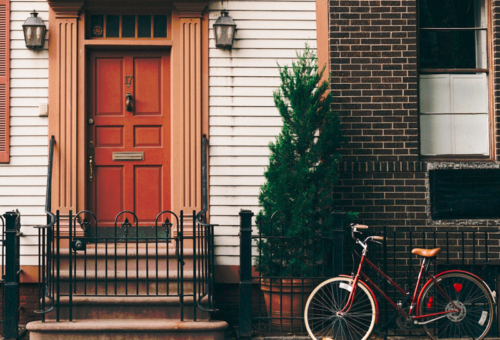 Porte d'entrée d'une maison mitoyenne de couleur brique avec vélo positionné devant pour parler de notre client Homeserve