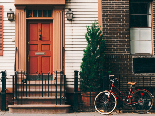 Porte d'entrée d'une maison mitoyenne de couleur brique avec vélo positionné devant pour parler de notre client Homeserve