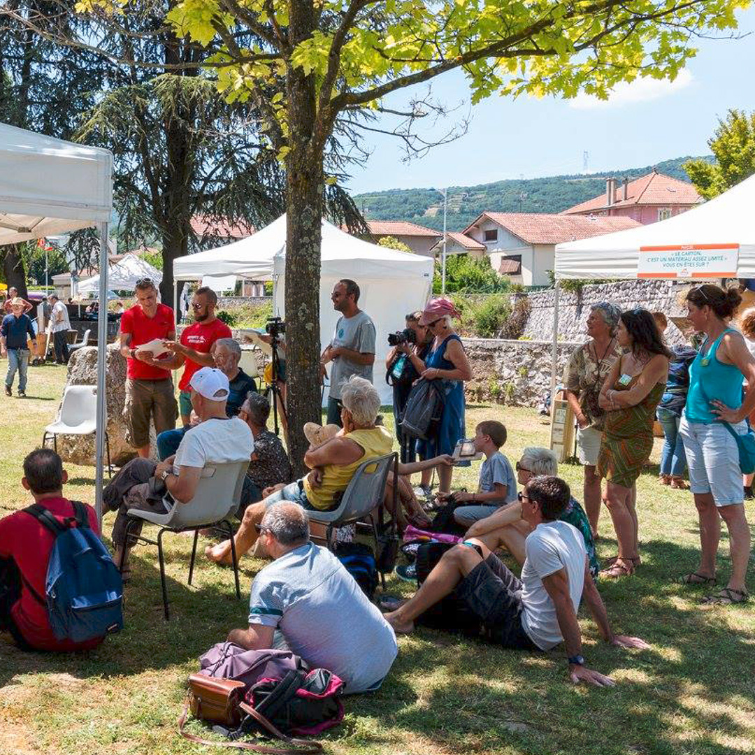 Plan large du village du Crussol Festival avec des personnes à l'ombre d'un arbre assis par terre