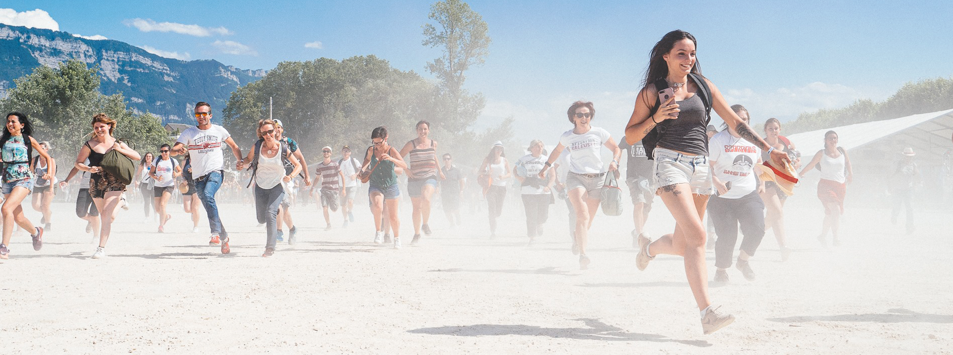 Photographie de personnes qui courent dans la poussière en direction du festival Musilac