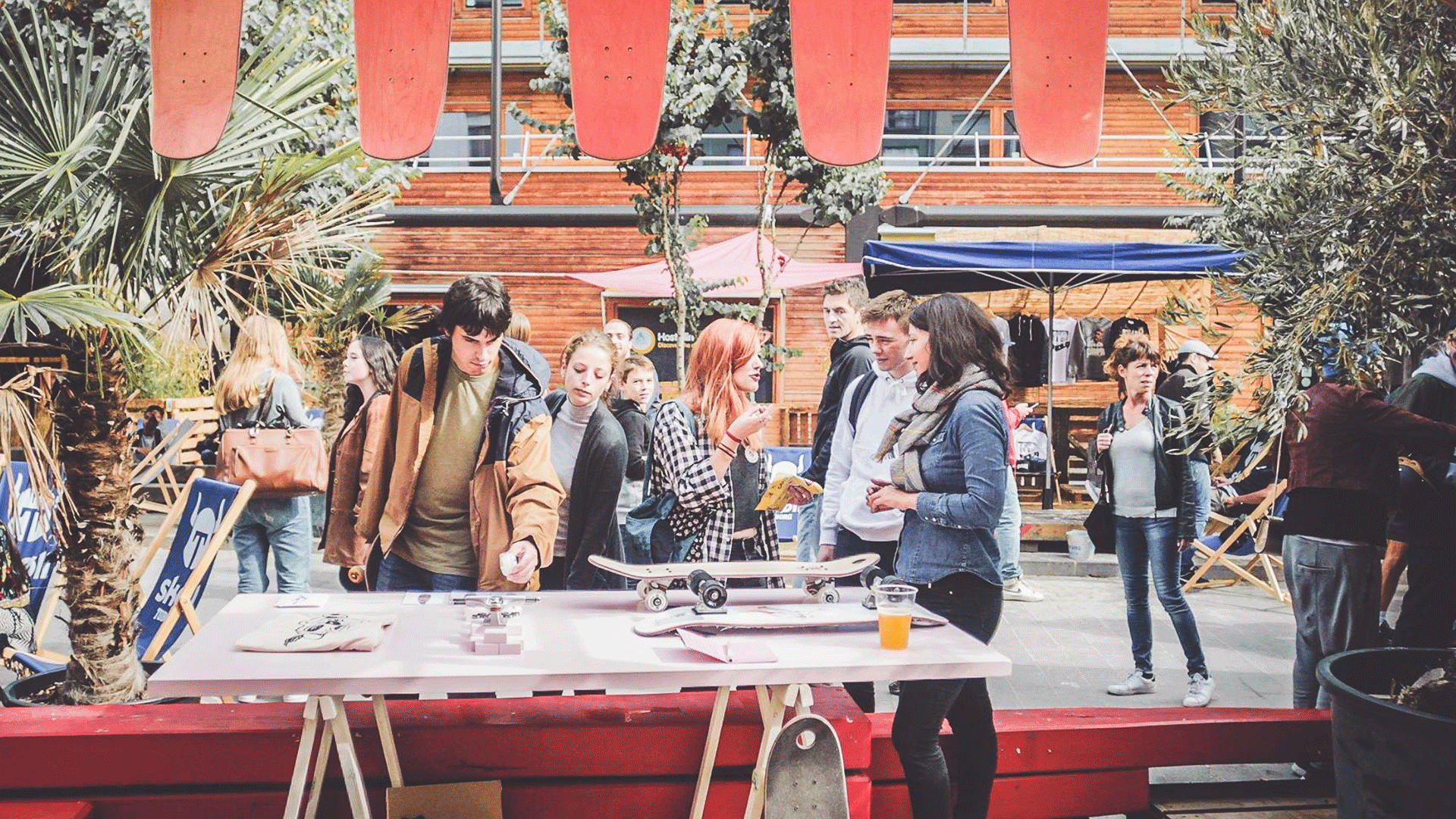 Personnes sur un stand du festival en train de regarder les skateboards et de discuter.