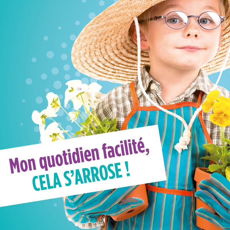 Gros plan sur un petit garçon à lunette en tenue de jardinier qui tient de pots de fleurs dans ses mains