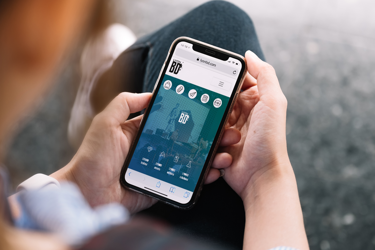 Personne qui tient un Téléphone portable ouvert sur le site internet de Lyon BD