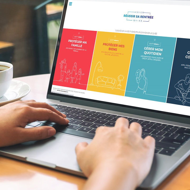 Personne dans un café avec le mains posées sur le clavier d'un ordinateur portable ouvert sur le site internet de Banque Populaire